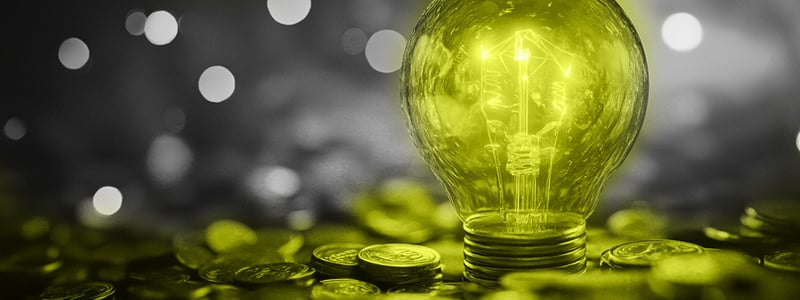A pile of coins with a glowing light bulb